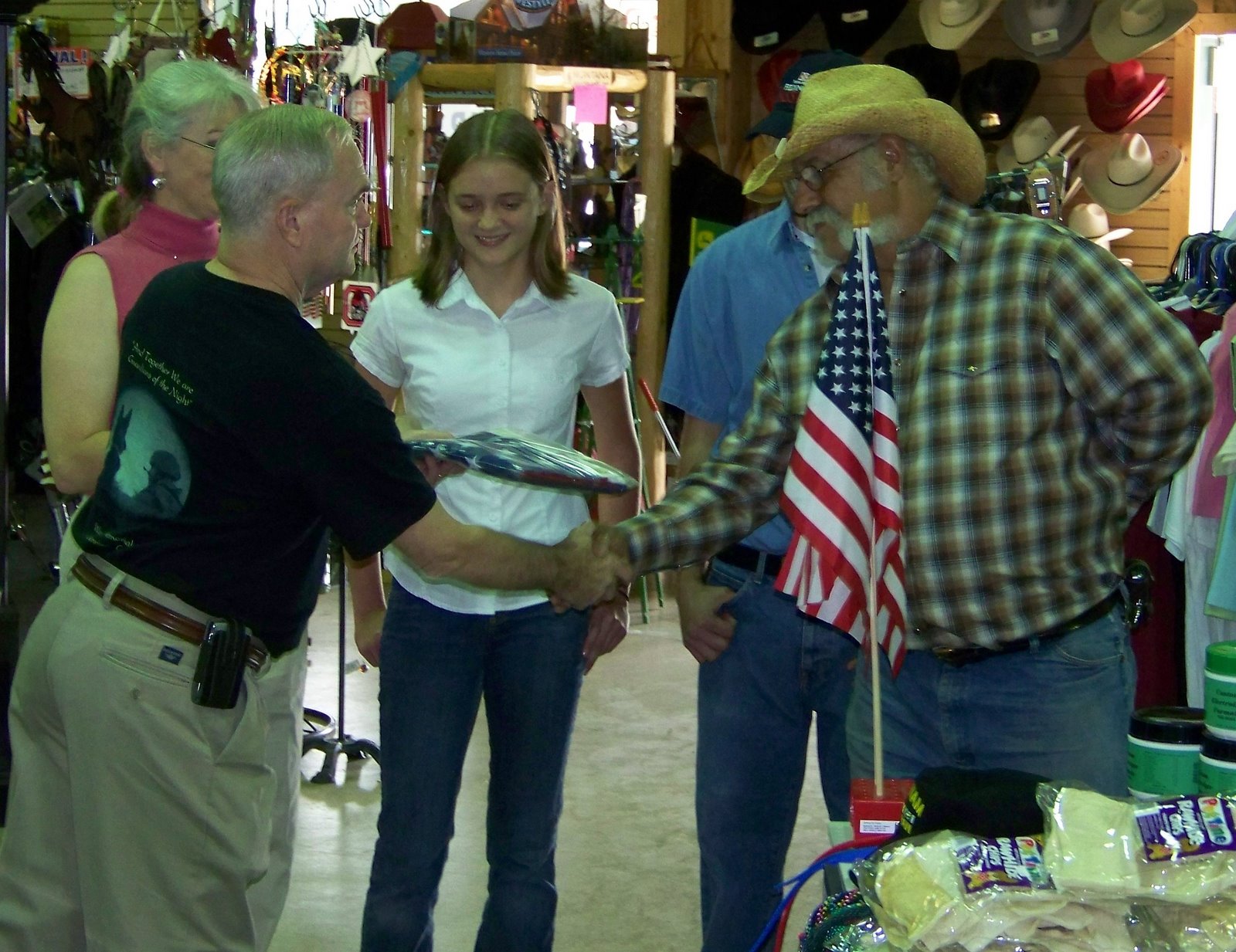 Ken Besecker presenting flag to Fabio Yepes. Sabine Yepes (store owner) and Jennifer O'Neill and Jeff Taylor (store employees) look on.