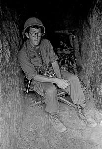 This black and white image shows Durrance sitting in a bunker with a camera in his lap.