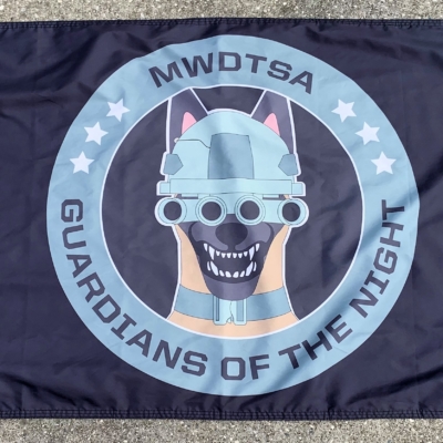 This image shows the MWDTSA Guardians of the Night flag laid out flat on a sidewalk.