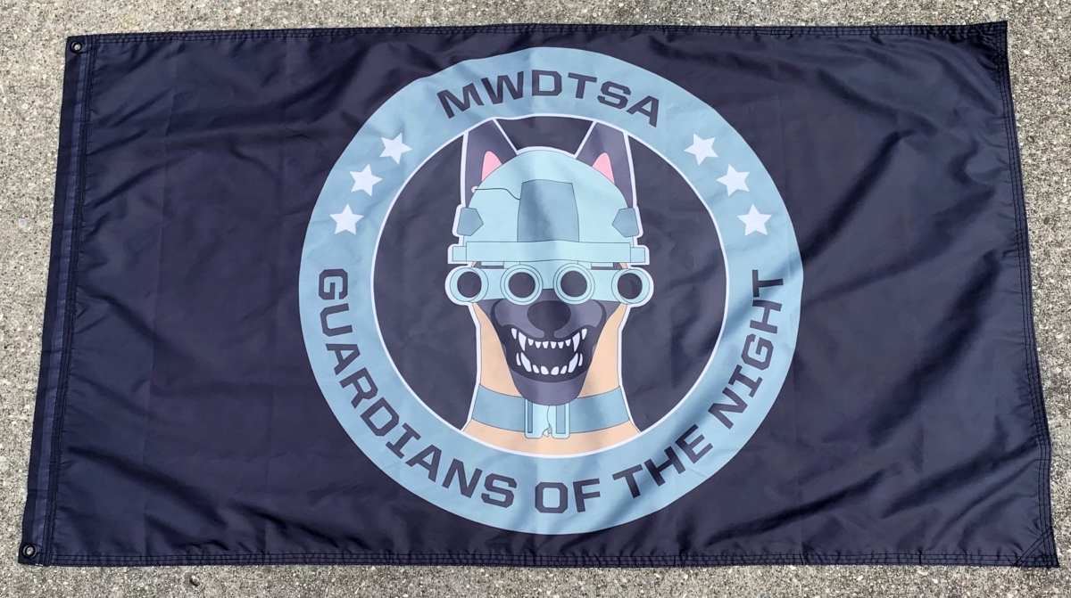 This image shows the MWDTSA Guardians of the Night flag laid out flat on a sidewalk.