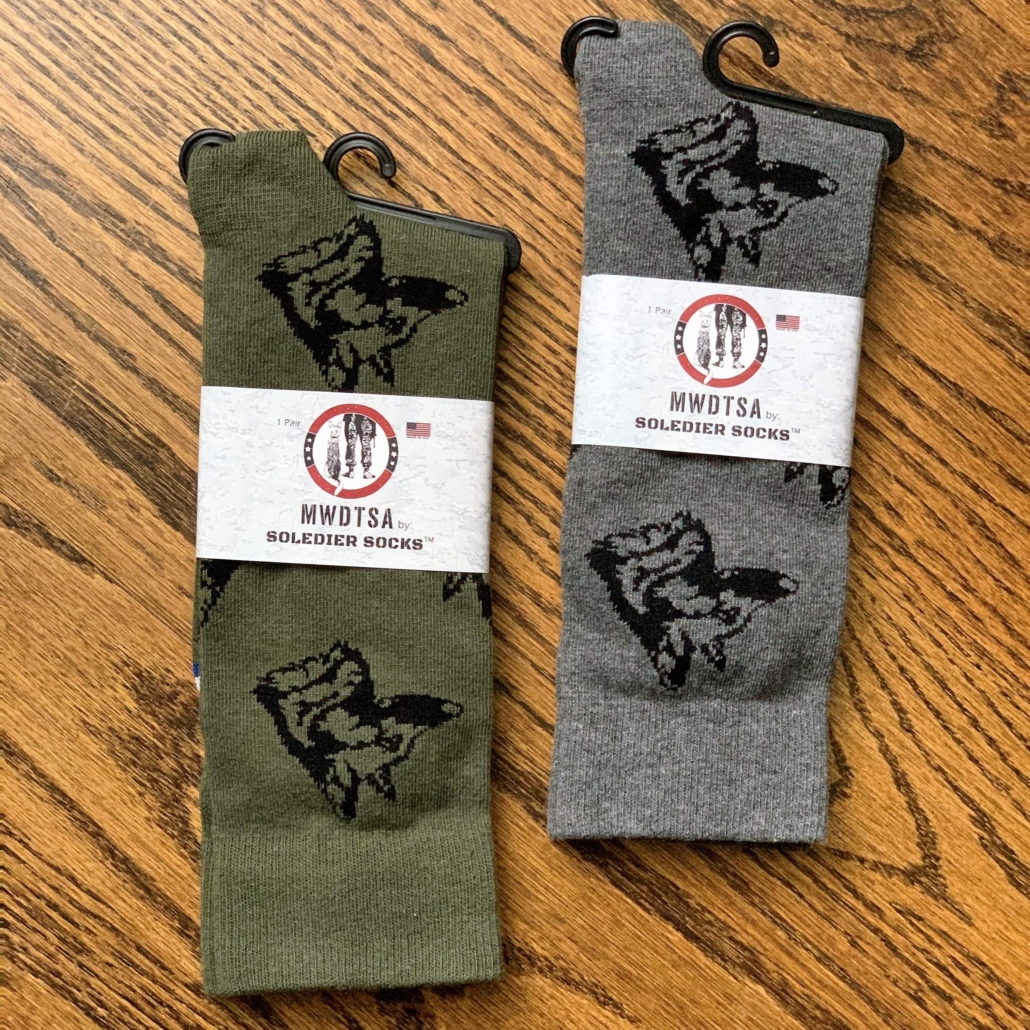 This photo shows two pairs of the handsome MMinto socks. MMinto's profile appears in a repeating pattern in black thread on the socks. This image shows the two available colors: olive and grey. This fundraiser will support U.S. military working dog s.