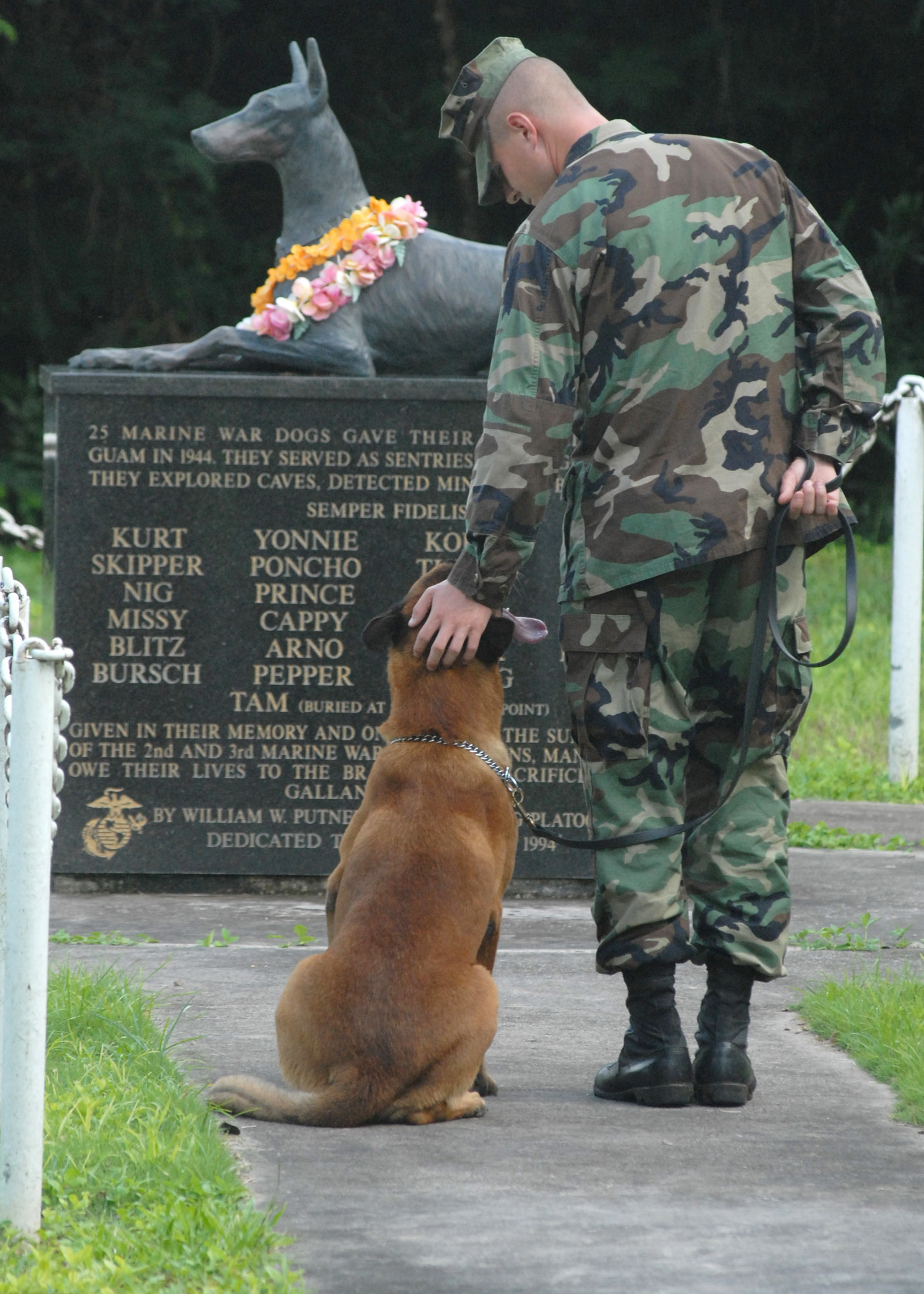 Handler and military working dog stand before MWD memorial on Guam.