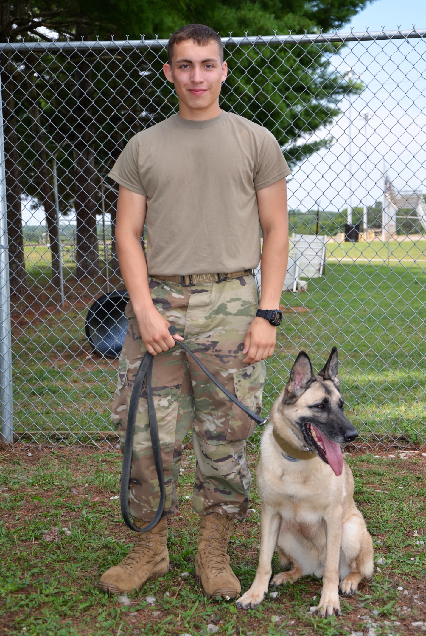 This photo shows a young Fort Campbell dog handler with his dog on leash.