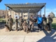 This photo shows handlers and their dogs, along with Security Forces Museum Director Ken Neal, standing in front of Nemo's Memorial at Lackland Air Force Base. In the background is a wreath donated by MWDTSA in honor of Vietnam veteran dog handler Bob Throneburg.