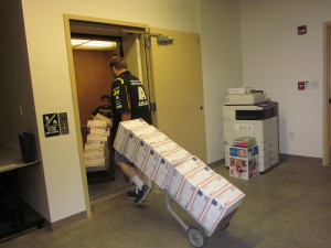 The Niwot, Colorado Postmaster and the young son of a Louisville Post Office employee wheel dollies full of care packages into an elevator on their way to the mail truck.